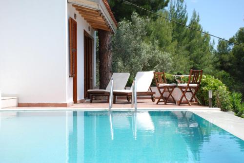 een zwembad met twee stoelen en een huis bij VILLA ISMINI, Skiathos in Skiathos-stad