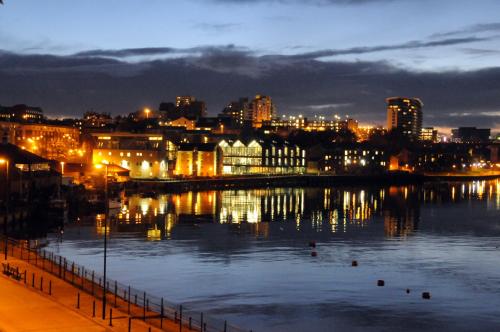 a city lit up at night with a body of water at Boars Head Boutique Hotel in Sunderland
