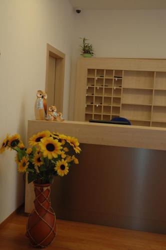 a vase filled with sunflowers sitting next to a shelf at Hotel Fiera in Bolzano