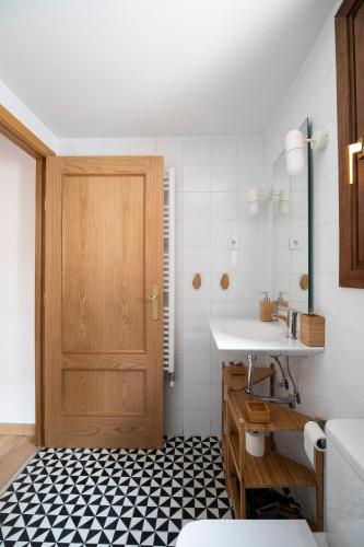 a bathroom with a sink and a wooden door at Inmocyma Casa Cervino, La Coma de Alba-Benasque in Benasque