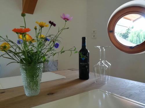 a bottle of wine and a vase of flowers on a counter at Großzügige helle Ferienwohnung bis 4 Personen in Chalampe, Elsass in Chalampé