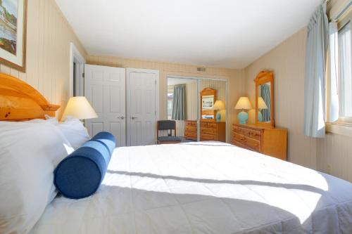 a bedroom with a large white bed with a blue object on it at Outer Banks Beach Club in Kill Devil Hills