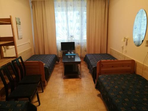 a room with three beds and a table and a television at Mahtra Hostel in Tallinn