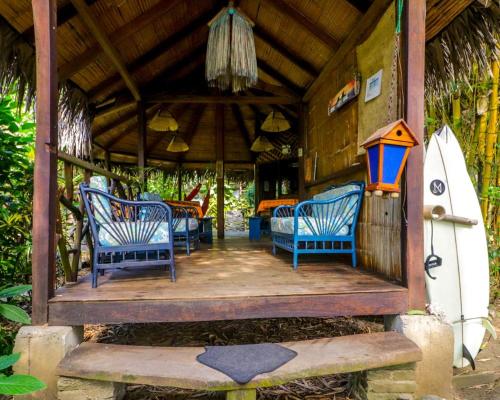 eine Veranda eines Hauses mit blauen Stühlen und einem Surfbrett in der Unterkunft Las Cabañas de la Iguana in Ayampe
