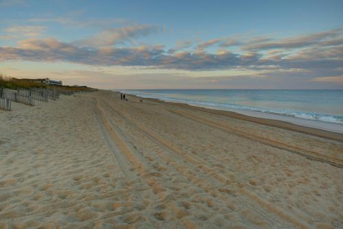 a beach with people walking on the sand and the ocean at Outer Banks Beach Club in Kill Devil Hills