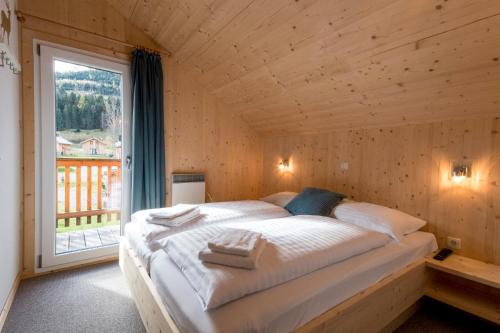 Cama en habitación de madera con ventana grande en Hirsch Chalet en Sankt Lorenzen ob Murau