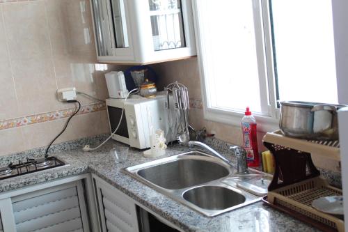 a kitchen counter with a sink and a microwave at City Apartment sur le port de Mahdia Free Wifi in Mahdia
