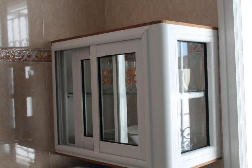 a white cabinet with two windows in a room at City Apartment sur le port de Mahdia Free Wifi in Mahdia