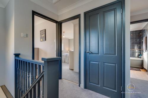 a hallway with a blue door and a staircase at The Buddha House Huntingdon Boutique Rooms in Godmanchester