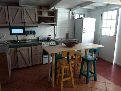 cocina con mesa de madera, sillas y nevera en El Tamarisco en Puerto Pirámides