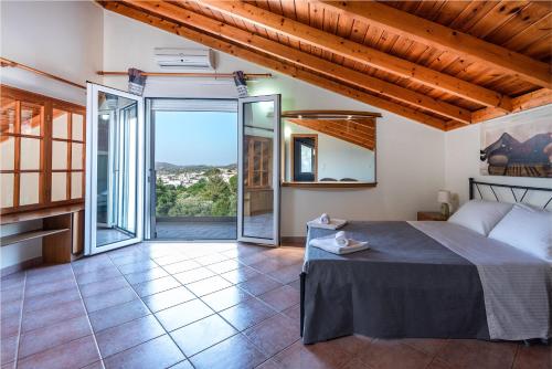 a bedroom with a bed and a large window at Villa Aphrodite in Pastida