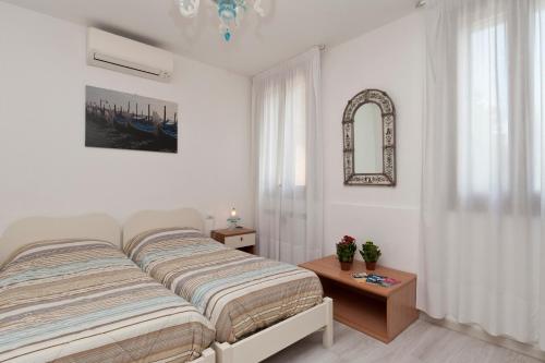 a white bedroom with a bed and a table at Ca' Del Pomo Grana' Al Roman in Murano