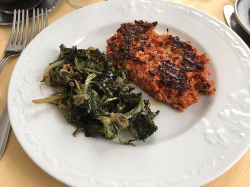 a white plate with a piece of meat and vegetables at Hotel La Congiura dei Baroni in Teggiano