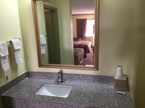 uma casa de banho com um lavatório e um espelho grande em Victorian Inn Midland em Midland
