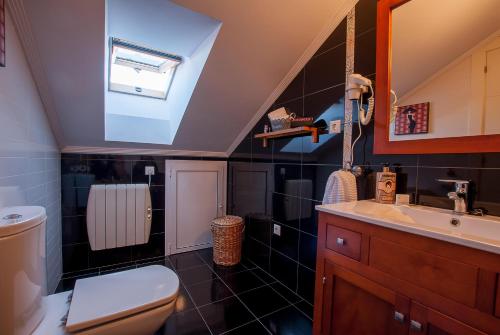 uma casa de banho com um lavatório, um WC e uma clarabóia em Atico Chic con Encanto em Muros de Nalón