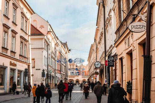 a group of people walking down a street with buildings at The Angels Apartments Krakow Old Town in Kraków