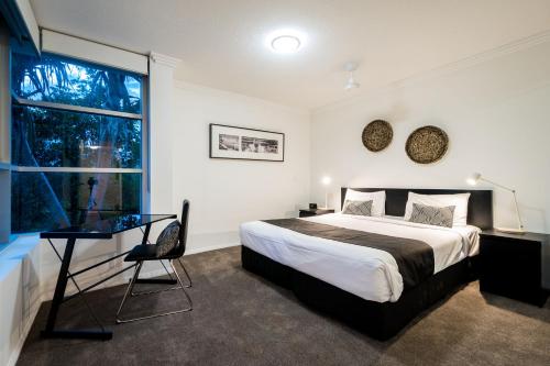a bedroom with a bed and a desk and a window at Chancellor Lakeside Apartments in Gold Coast