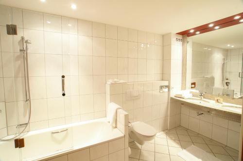 a bathroom with a tub and a toilet and a sink at Hotel Winzerstube in Ihringen