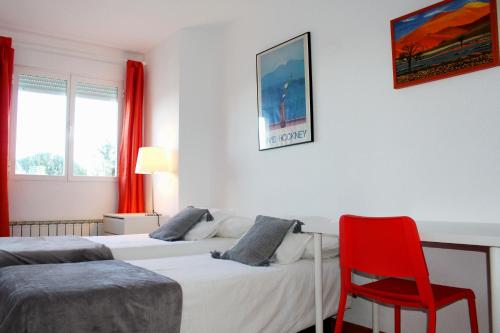 a bedroom with two beds and a red chair at Luminoso Piso en Navacerrada Wifi in Navacerrada