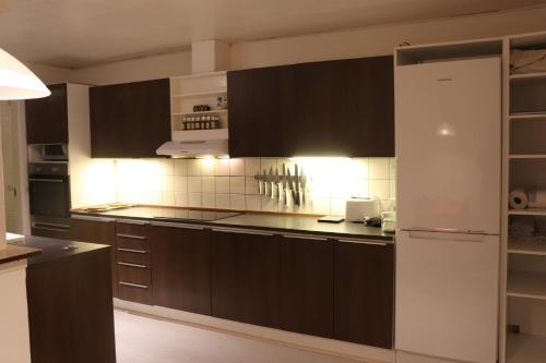 a kitchen with brown cabinets and a white refrigerator at Holstebro Townside House in Holstebro