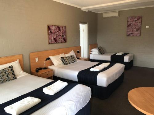 a hotel room with three beds and a table at Best Western Coachman's Inn Motel in Bathurst