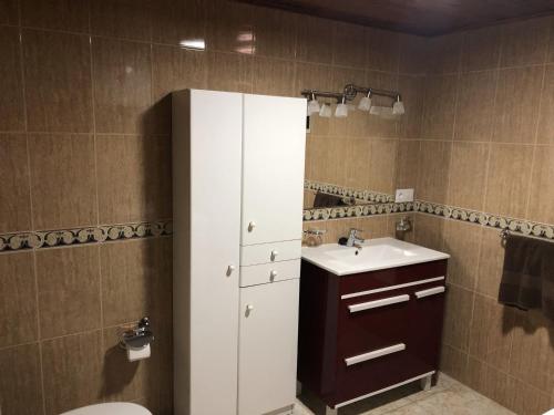 La salle de bains est pourvue d'une armoire blanche et d'un lavabo. dans l'établissement Apartamentos Acorán Mogán, à Mogán