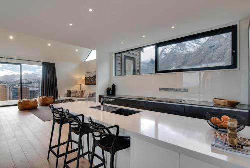 a kitchen with a white counter and stools at 4 Stockyard Lane by Sotheby's Luxury Rental Homes in Queenstown