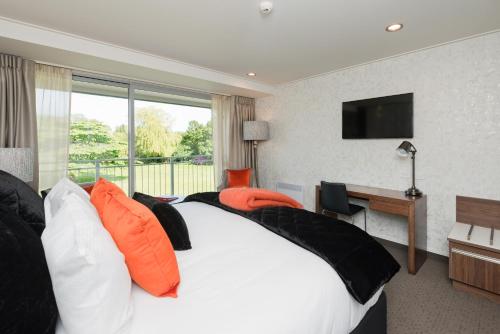 a bedroom with a bed and a desk and a television at Croydon Lodge in Gore