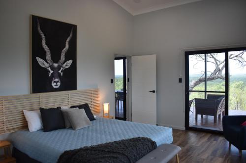 een slaapkamer met een bed met een foto van een hert aan de muur bij Ironbark House in Dimbulah