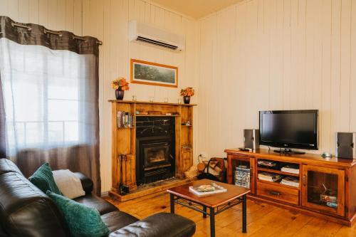 a living room with a couch and a television at Apple Blossom Cottages in Stanthorpe