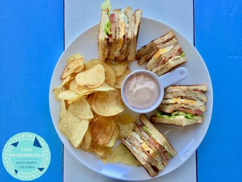 a plate with a sandwich and chips and a cup of coffee at Casa Mediterranea in Santa Marta