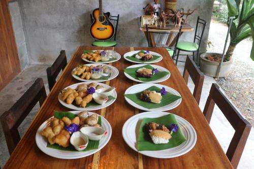 uma mesa de madeira com pratos de comida em BaanRaiChayKhaoFarmStay em Nakhon Si Thammarat