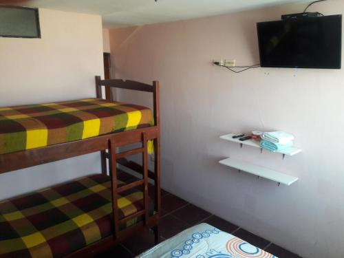 a room with two bunk beds and a flat screen tv at Hostal Haziel in Salinas