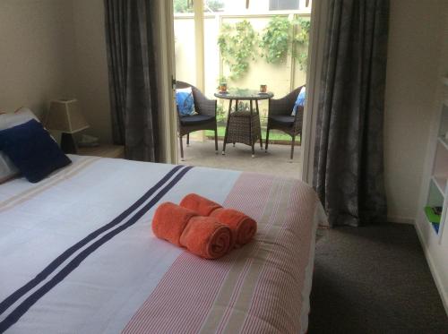 een slaapkamer met een bed met oranje handdoeken erop bij Albert Mews B and B in Whitianga