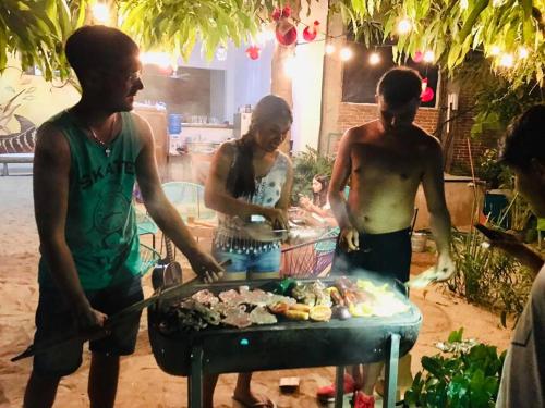 a group of people preparing food on a grill at Paziflora Hostel -STARLINK- in Puerto Escondido