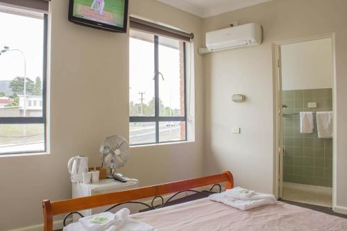 1 dormitorio con cama, ducha y TV en Figtree Hotel Wollongong, en Wollongong