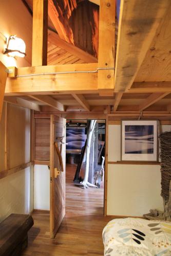 a room with a bed and a wooden ceiling at Gallery Stay Kitashajin in Higashikawa