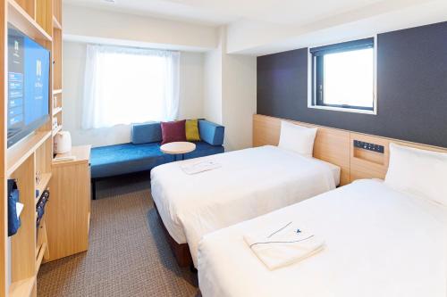 a hotel room with two beds and a tv at hotel MONday Tokyo Nishikasai in Tokyo