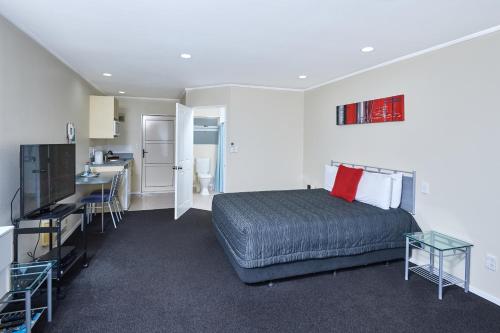 a bedroom with a bed and a kitchen with a sink at Livingston Motel in Whakatane