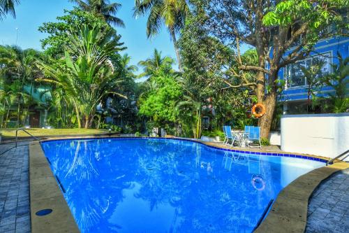 a large blue swimming pool with palm trees in the background at Villa Samaara9 Candolim Beach in Candolim