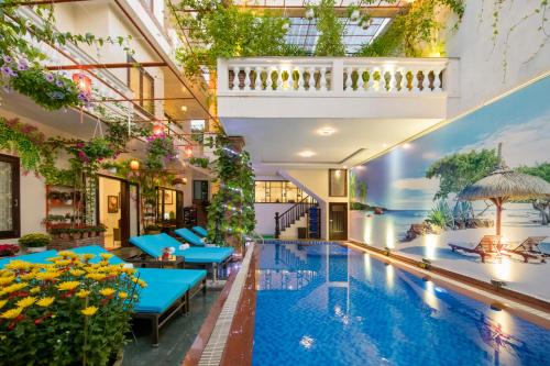 uma piscina interior num edifício com mesas azuis em Pham Gia Boutique Villa em Hoi An