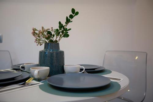 a table with plates and cups and a vase with flowers at Yellow Apartment in Cluj-Napoca
