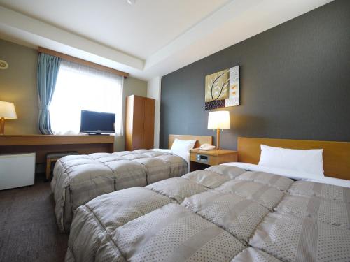 a hotel room with two beds and a window at Hotel Route-Inn Court Fujioka in Fujioka
