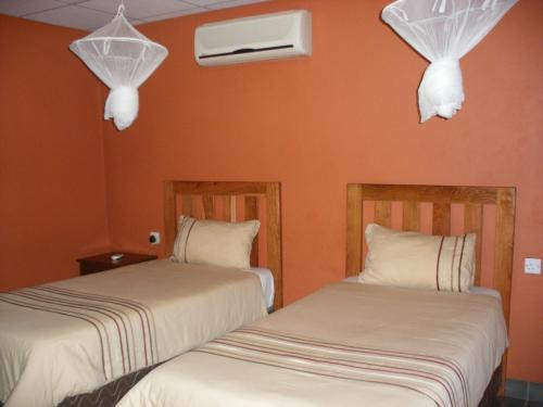 two beds in a room with orange walls at Gloria's Bed and Breakfast in Livingstone