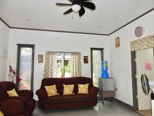 a living room with two couches and a ceiling fan at Calunsag Residence in Siquijor