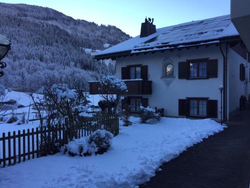 una casa con nieve en el suelo junto a una valla en Apartment Allegra, en Küblis