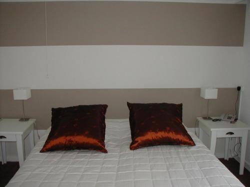 a white bed with two red pillows and two tables at Hotel van Dijk in Kampen