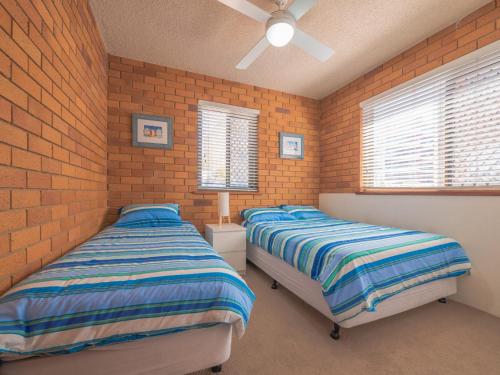- 2 lits dans une chambre dotée de murs en briques et de fenêtres dans l'établissement San Clemente 3 24 Orvieto Tce, à Caloundra