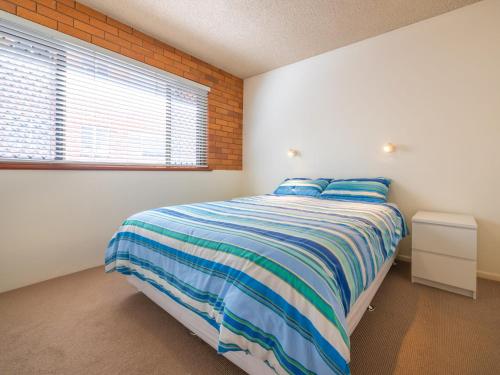 a bedroom with a bed with blue and white stripes at San Clemente 3 24 Orvieto Tce in Caloundra