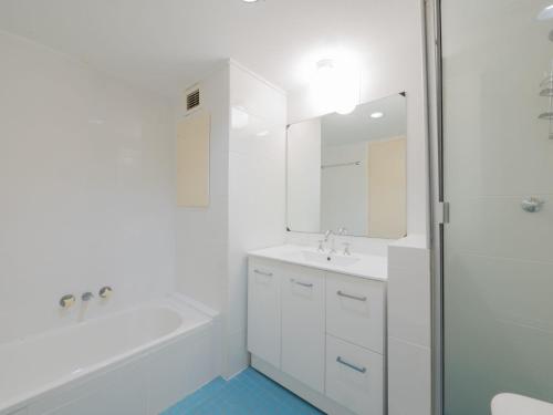 a white bathroom with a tub and a sink and a shower at Seaspray U4 21 Warne Tce in Caloundra
